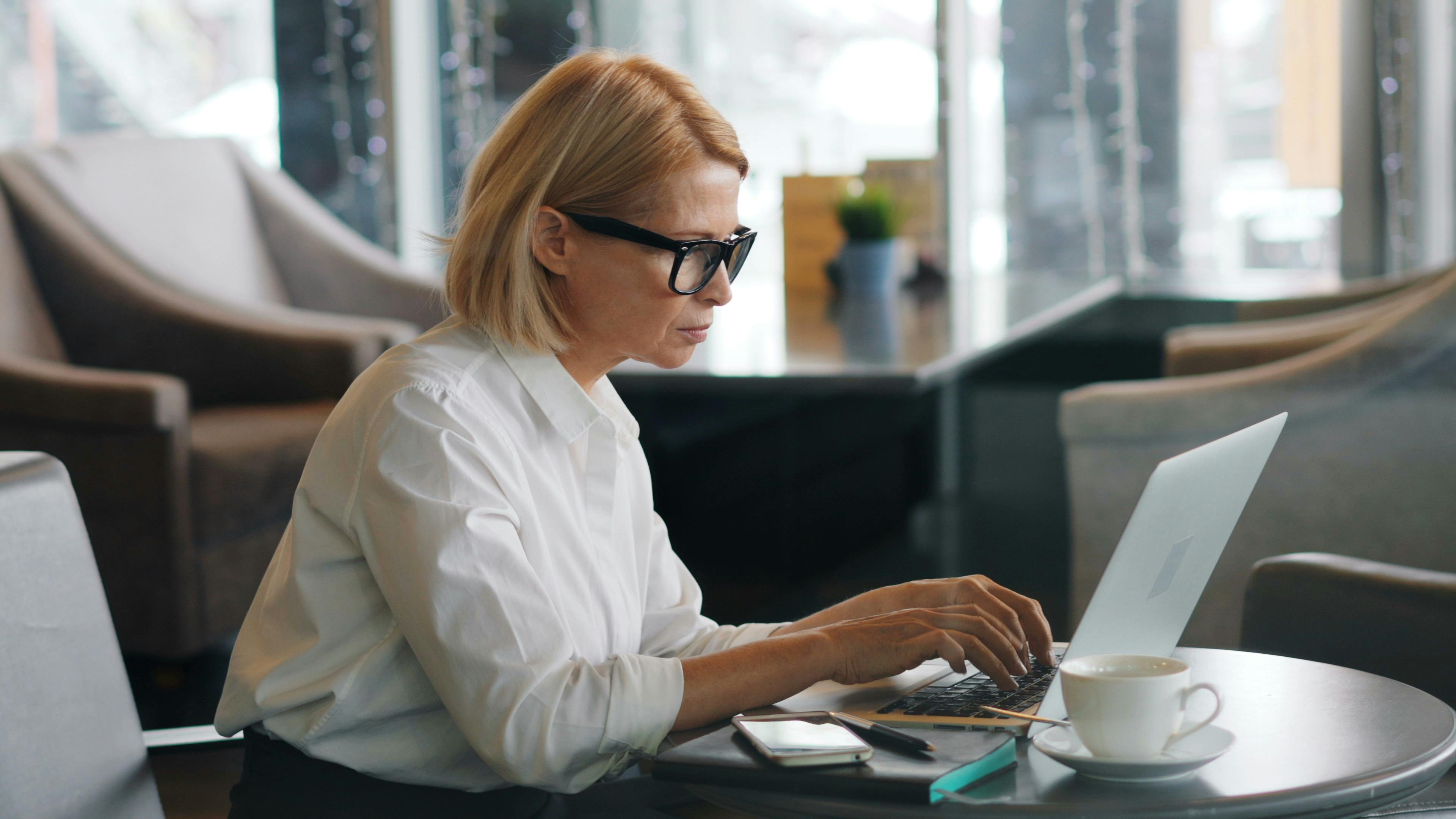 a woman in glasses is working on her laptop