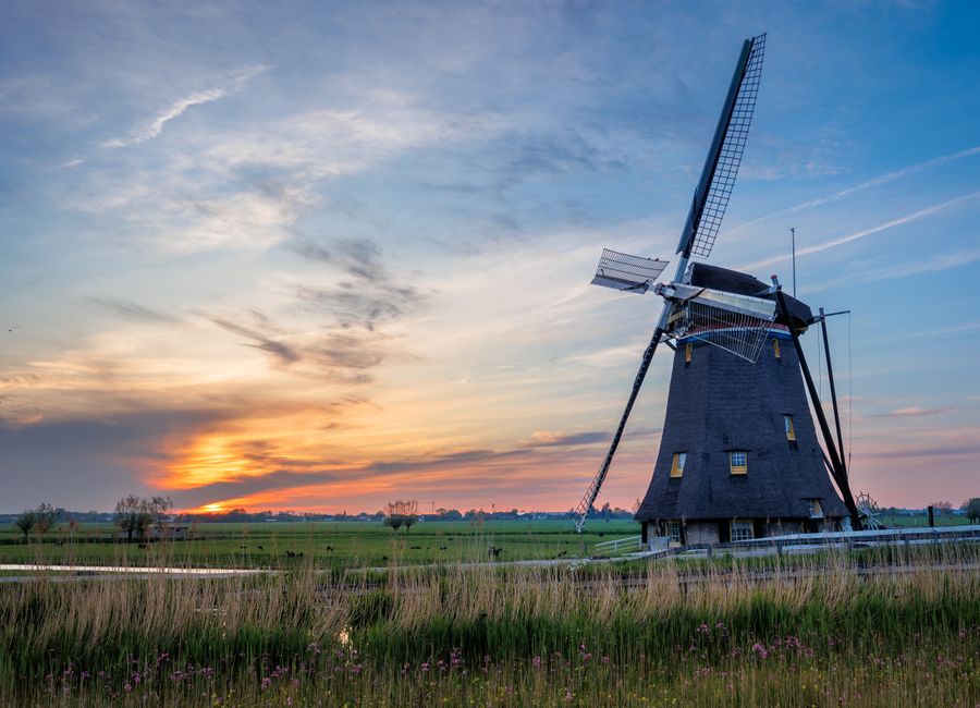 Capture of a classic Dutch windmill in Maasland at sunset, offering a picturesque rural landscape.