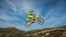 一名越野摩托车手在户外穿着彩色装备表演跳高