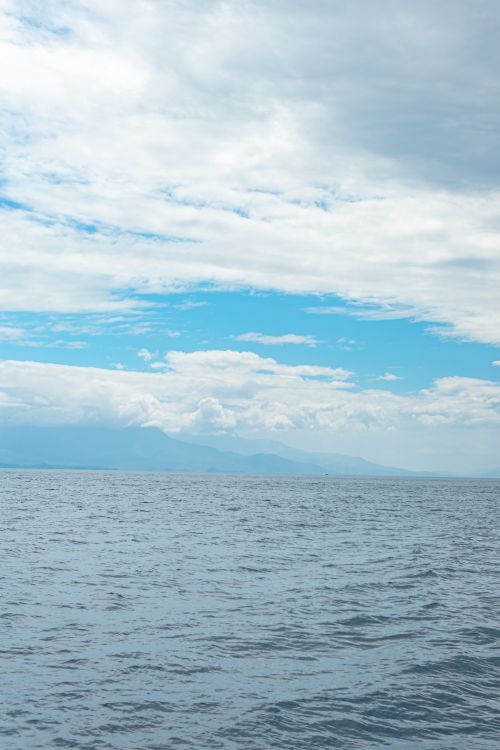 Free Peaceful ocean scene with a vast cloudy sky horizon, perfect for nature and travel themes. Stock Photo