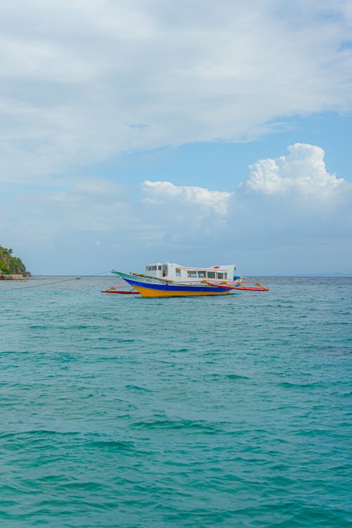 A boat is floating in the ocean near a beach