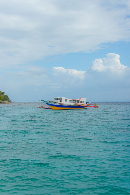 Free Captivating view of a colorful traditional boat on calm coastal waters under a bright sky. Stock Photo