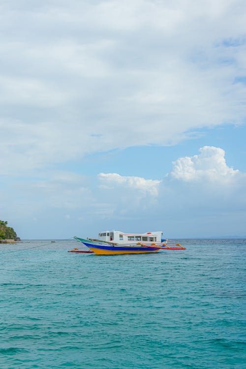 A boat is floating in the ocean near a beach