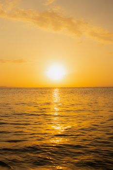 Peaceful sunrise with golden hues reflecting on the serene ocean waves.