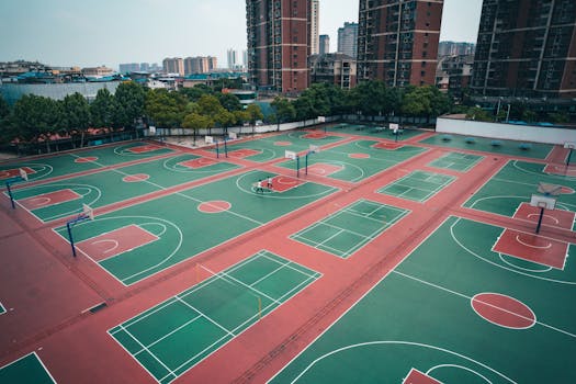 Aerial shot of multiple basketball courts in a residential area of Jiujiang, surrounded by skyscrapers.