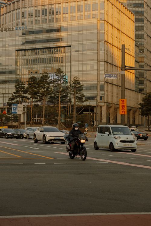 Free Motorcyclist navigating through city traffic during sunset, capturing the vibrant urban lifestyle. Stock Photo