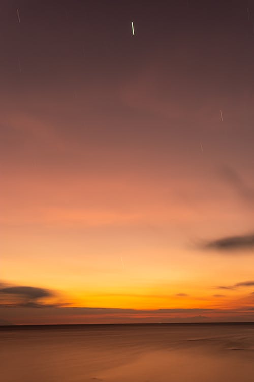 A sunset with a shooting star in the sky