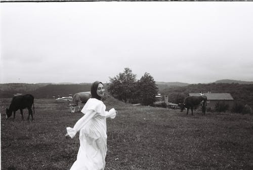 A woman in a white dress walking through a field