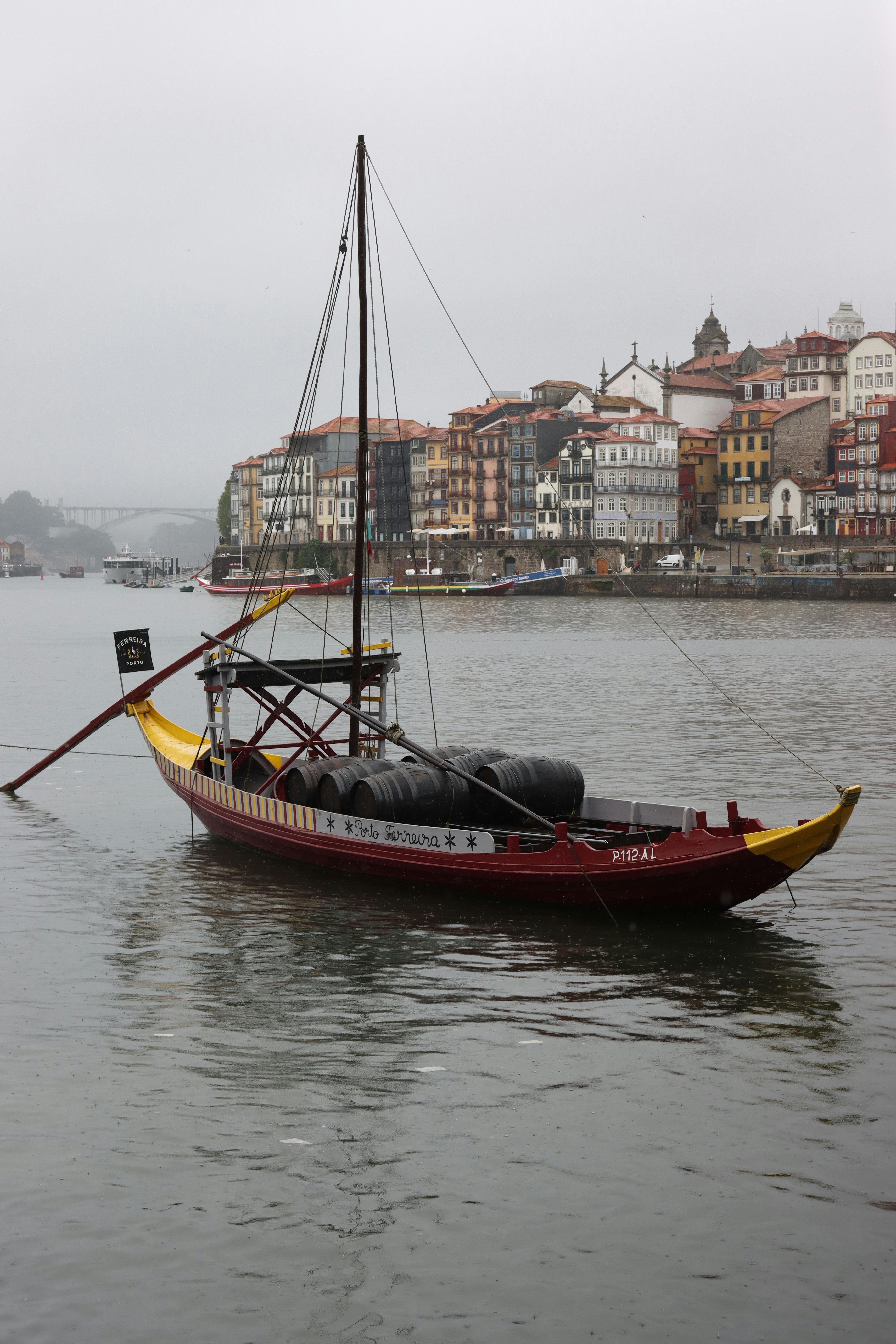 Rabelo boat on Douro River with Porto's colorful houses in the background.