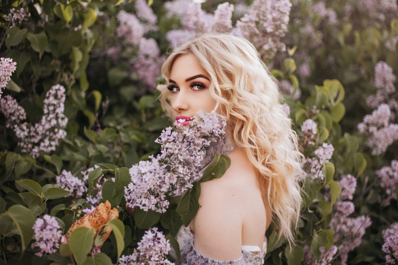 elegant blonde woman standing amidst blooming lilacs captivating outdo