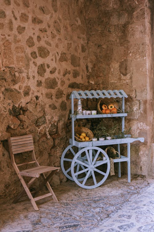 A blue cart with a chair and a bowl of fruit