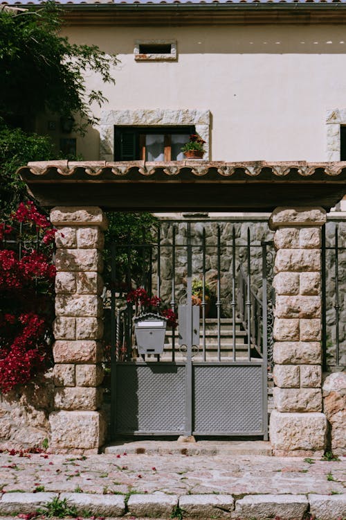 A gate with flowers and a stone wall