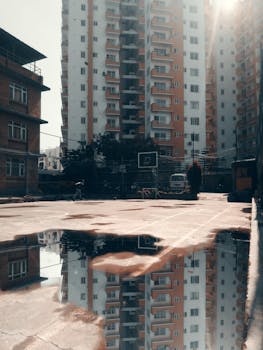 A reflective urban scene in Kathmandu showcasing apartment buildings around a puddle