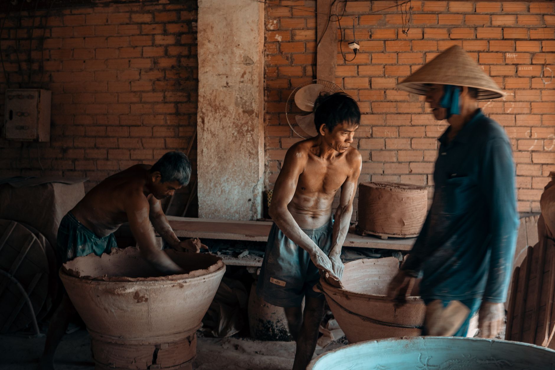 A group of craftsmen working on handmade pottery in a traditional workshop setting.