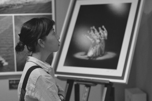 A woman gazing at a black and white painting in an art gallery setting. Capturing art appreciation.