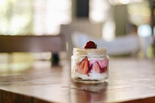 Free Delicious strawberry yogurt parfait in a clear jar on a wooden table, highlighting freshness and creamy textures. Stock Photo