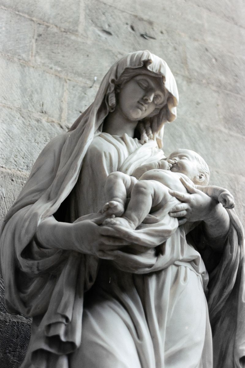 Close-up stone statue of Virgin Mary holding baby Jesus inside Rouen Cathedral showing intricate sculptural detail