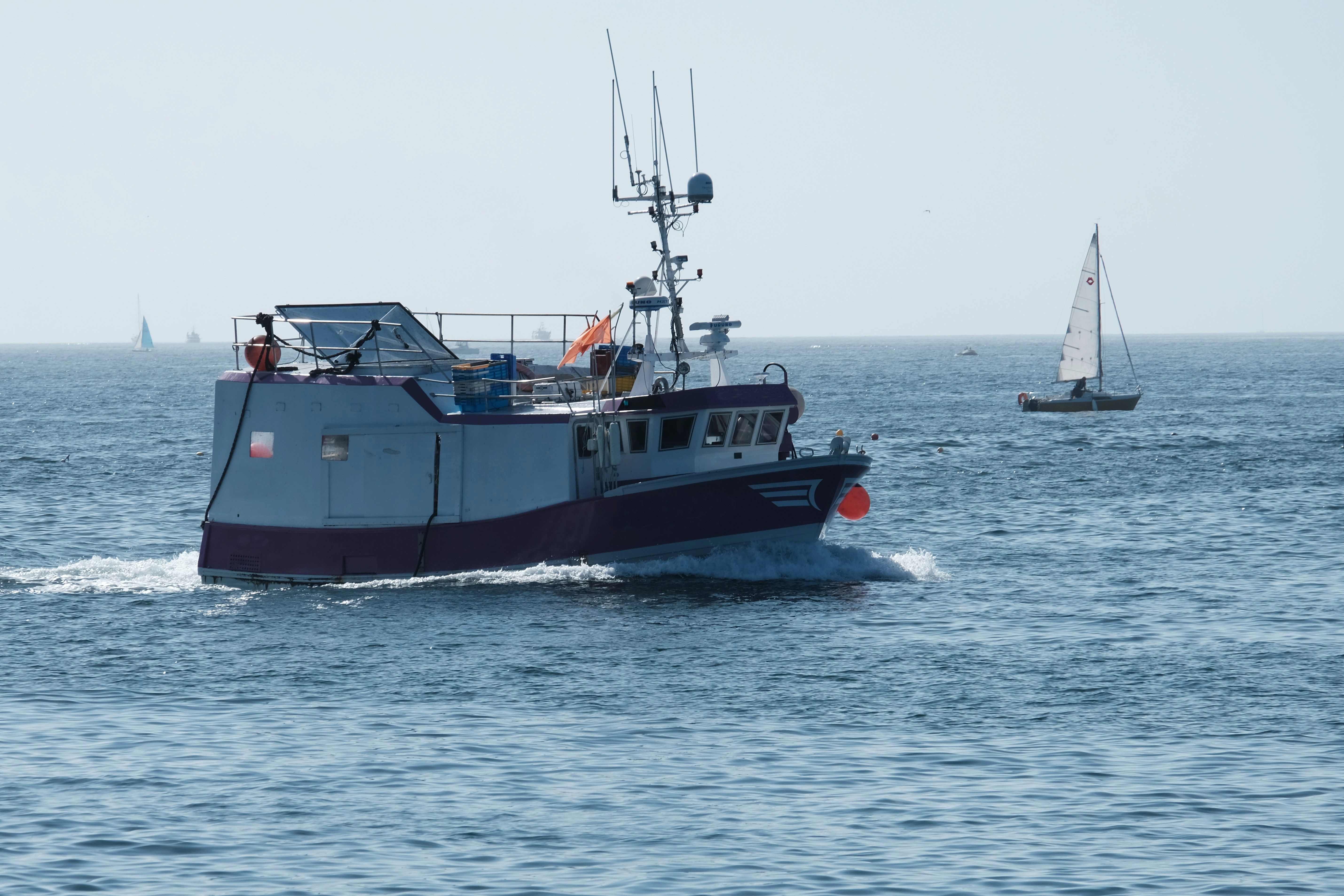 Bateau de pêche naviguant sur une mer calme au petit matin, départ vers les zones de pêche