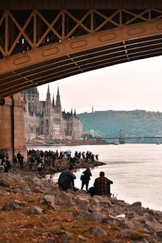 黄昏时分，人们沿着多瑙河，在布达佩斯标志性的议会大楼旁放松身心