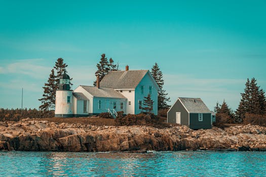 Scenic view of a coastal lighthouse and house on rocky shores in Maine, USA. Ideal for travel inspiration.