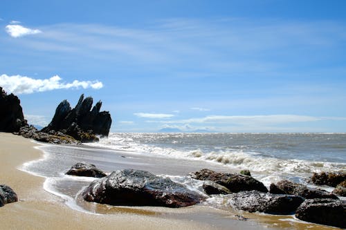 A sandy beach with rocks and a blue sky