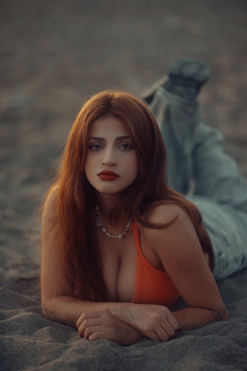 A woman with red hair laying on the beach