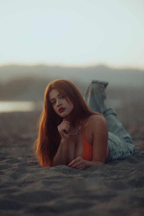 A woman laying on the beach with her hair in her face