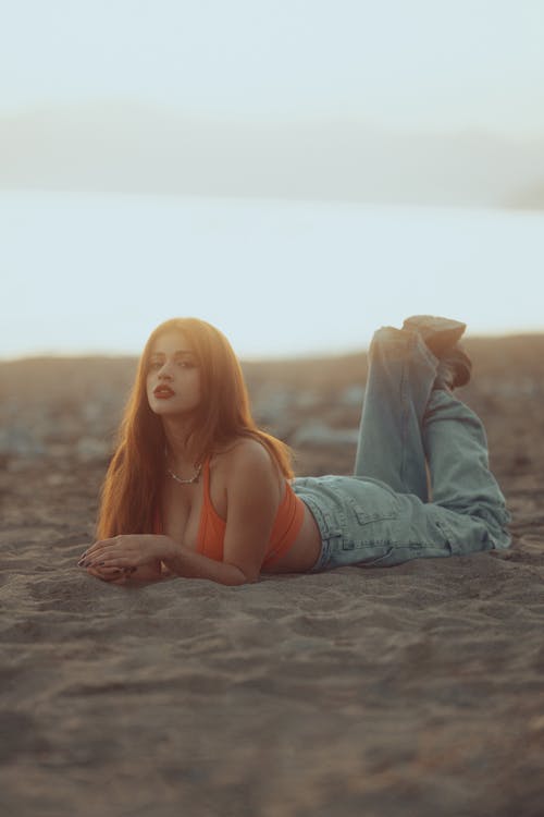 A woman laying on the beach with her legs spread