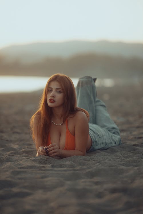 A woman laying on the beach in an orange top
