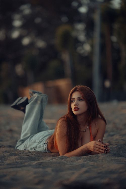 Free A woman with long hair poses elegantly on a beach during the warm summer evening. Stock Photo