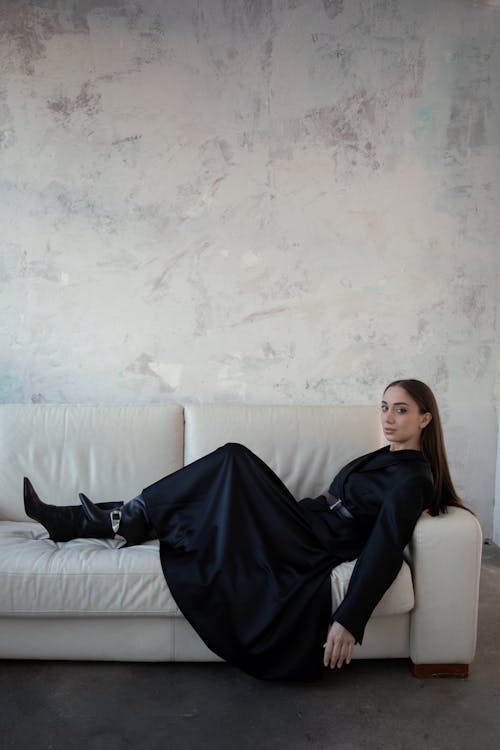 A woman in a black dress laying on a couch