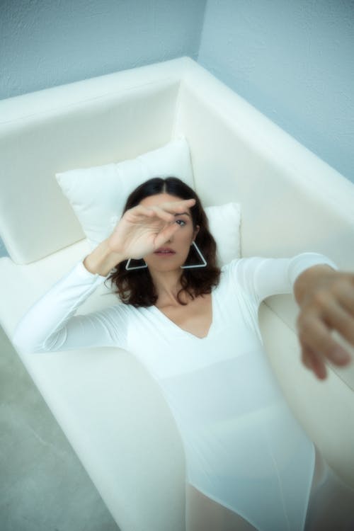 Woman Lying Down on Sofa in White Bodysuit