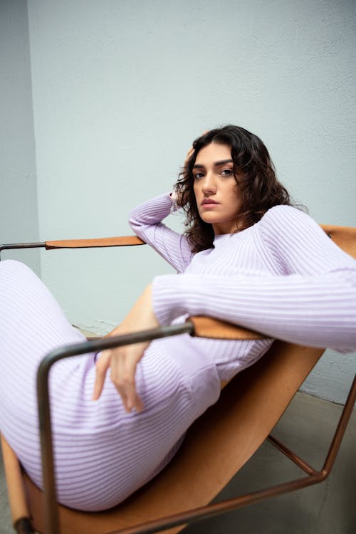 A woman in a purple sweater is sitting on a chair
