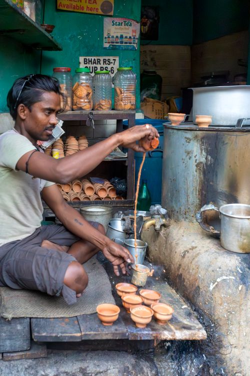 Free Indian tea vendor pouring chai into clay cups in a street stall. Stock Photo