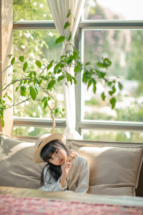 A little girl sitting on a couch with a plant