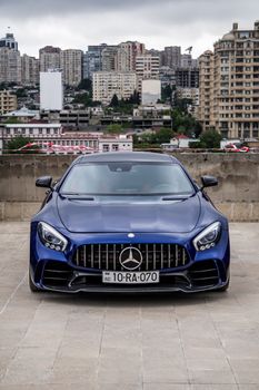 Luxurious blue Mercedes AMG GT captured against Azerbaijan's vibrant Baku skyline.