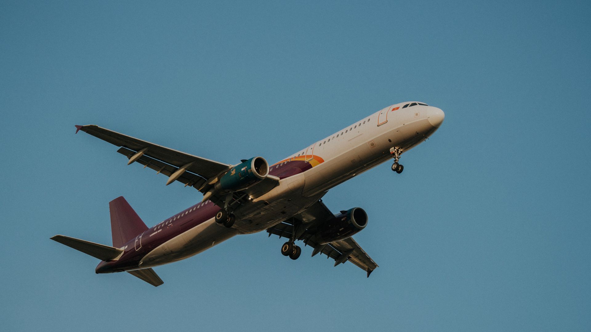 modafinil for jet lag recovery: Boost Energy, Focus, and Productivity Low-angle view of a commercial airplane flying against a clear blue sky, showcasing its wings and fuselage — modafinil for jet lag recovery