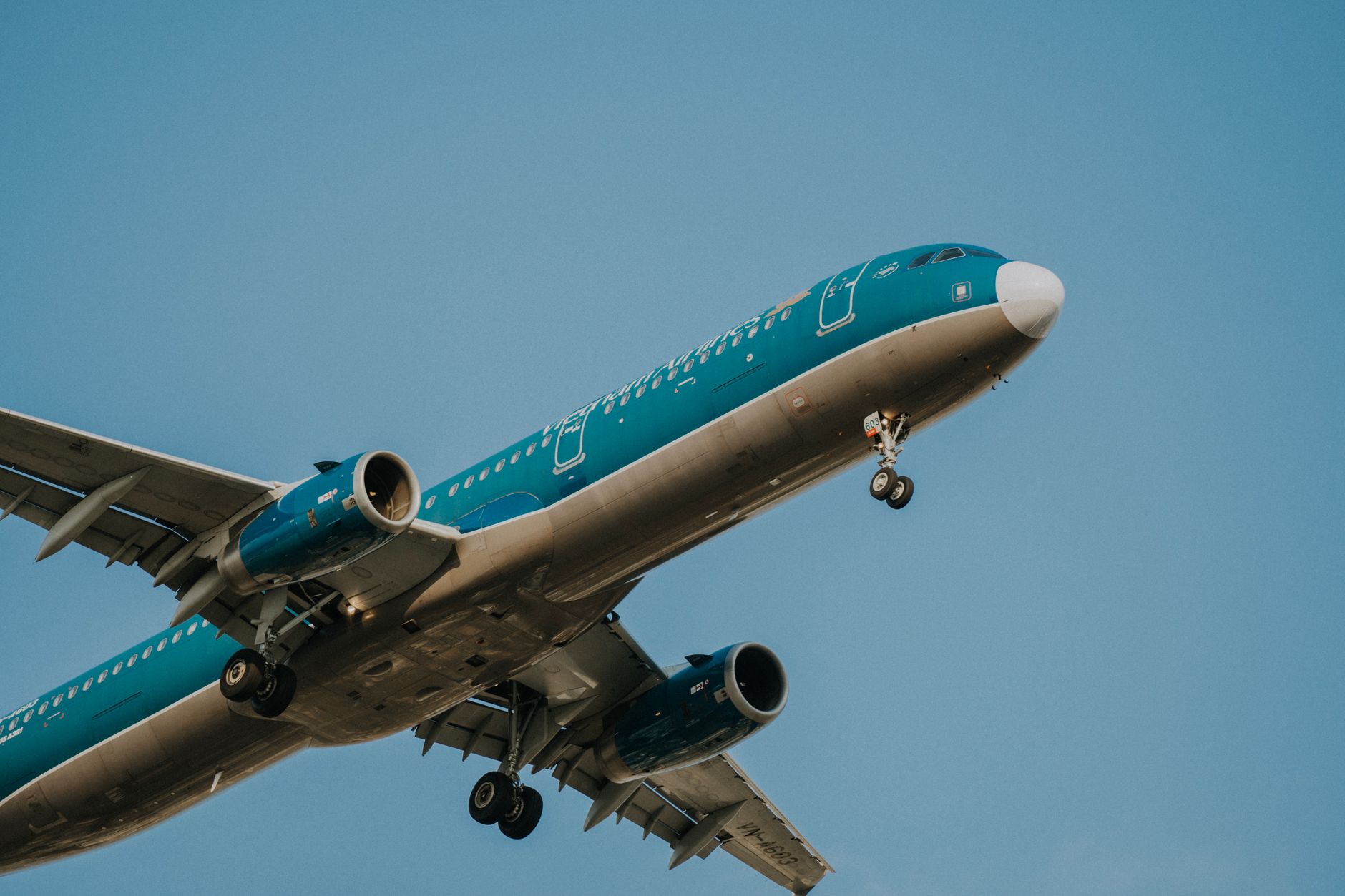 A Vietnam Airlines passenger airplane in flight, clear blue sky backdrop.
