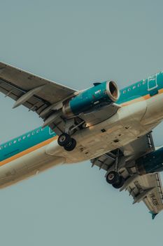 Detailed low angle shot of airplane soaring in a clear blue sky, emphasizing its undercarriage and structure.