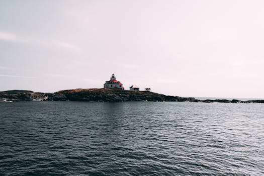 A picturesque lighthouse on a rocky island during dusk against a tranquil sea.