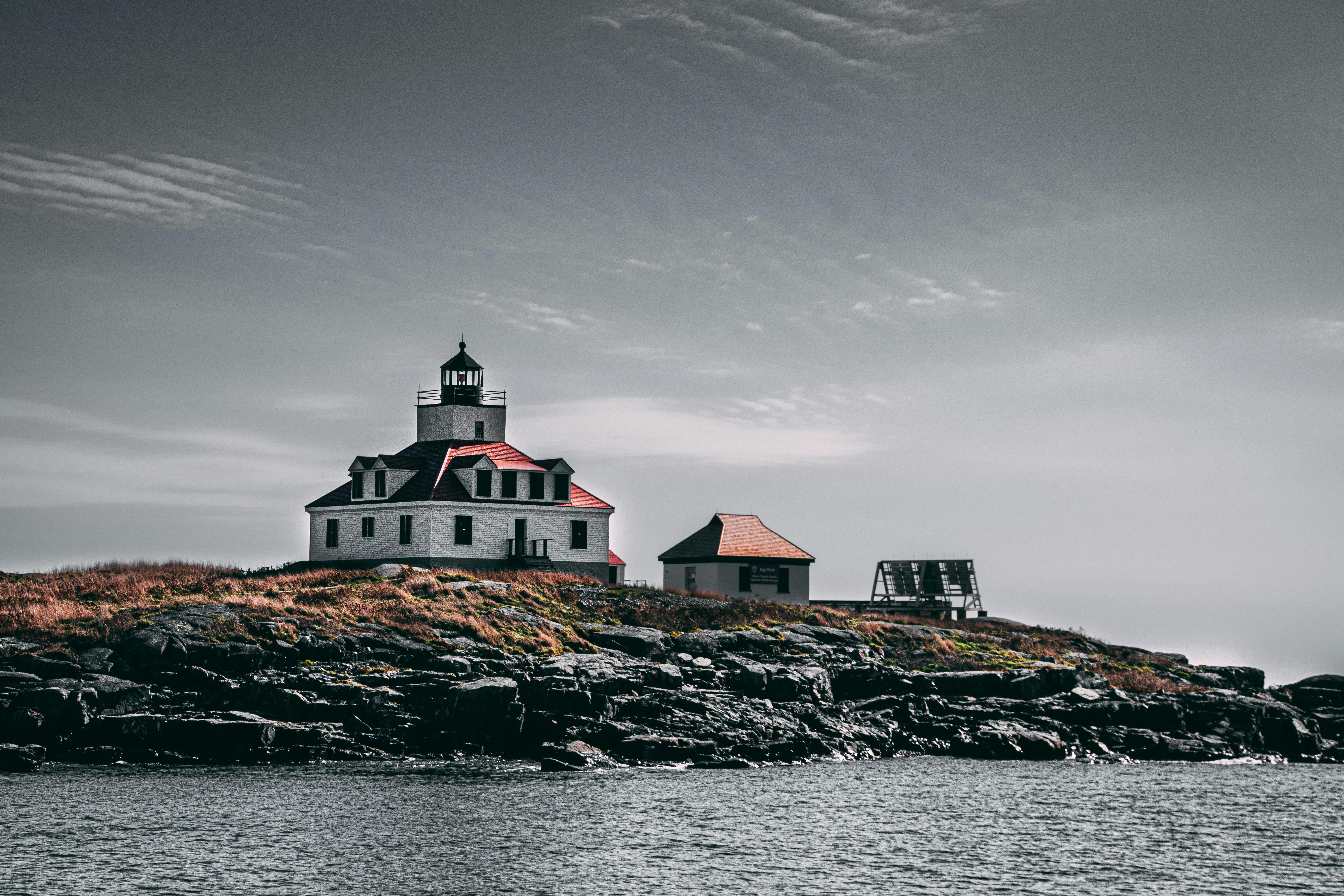 一座风景如画的灯塔矗立在晴朗天空下的岩石岛屿上