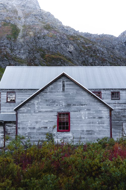 A gray building with red trim and a mountain in the background