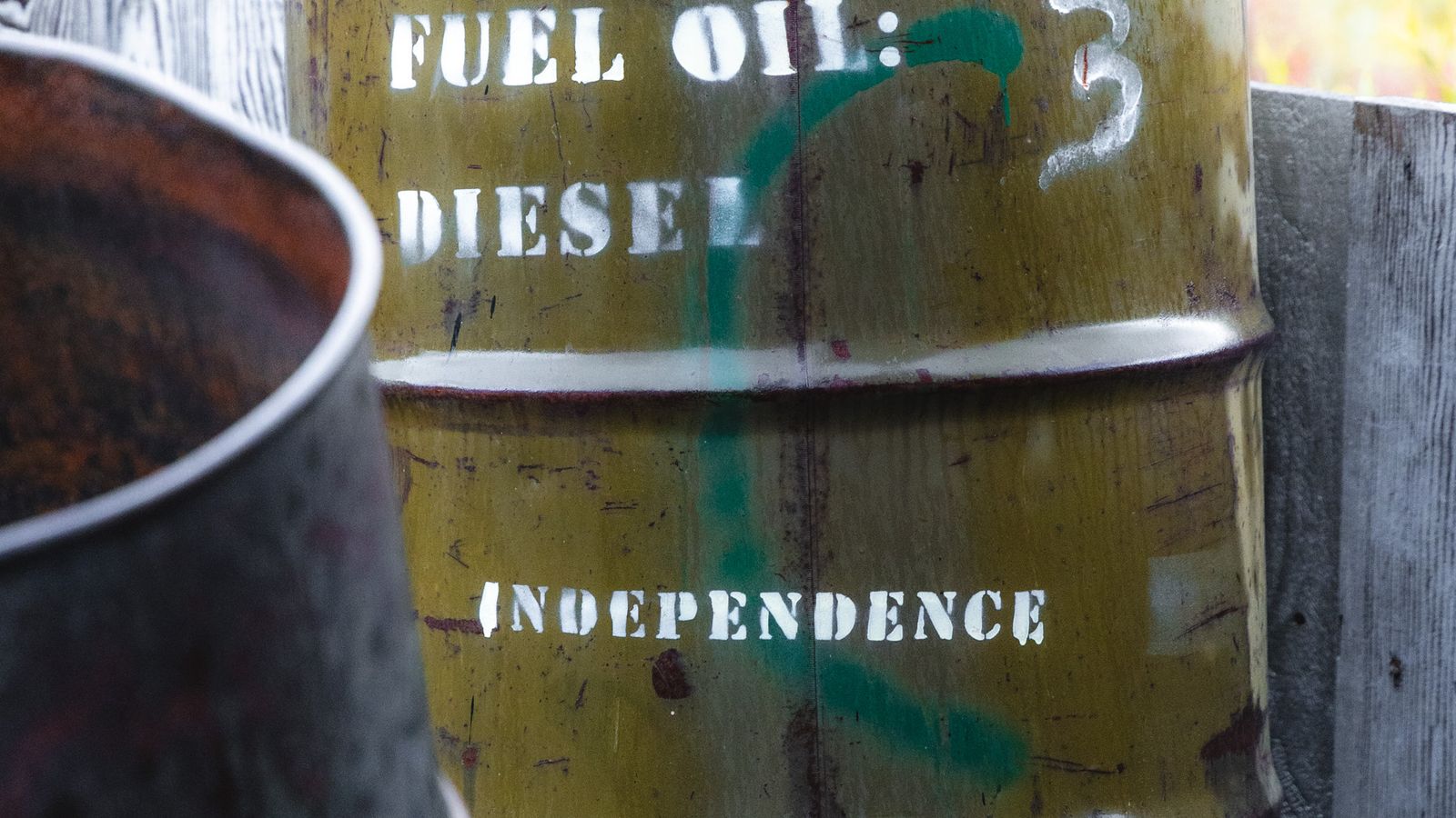 田園地帯に置かれた「Diesel」と表示された燃料用ドラム缶。原油高と景気減速が重なるスタグフレーション懸念を象徴するイメージ。