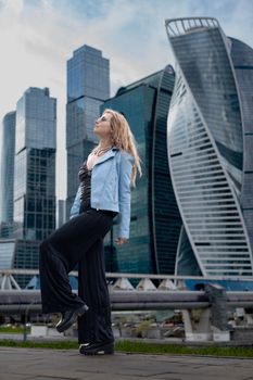 Stylish woman in urban setting, showcasing modern fashion against city skyscrapers.