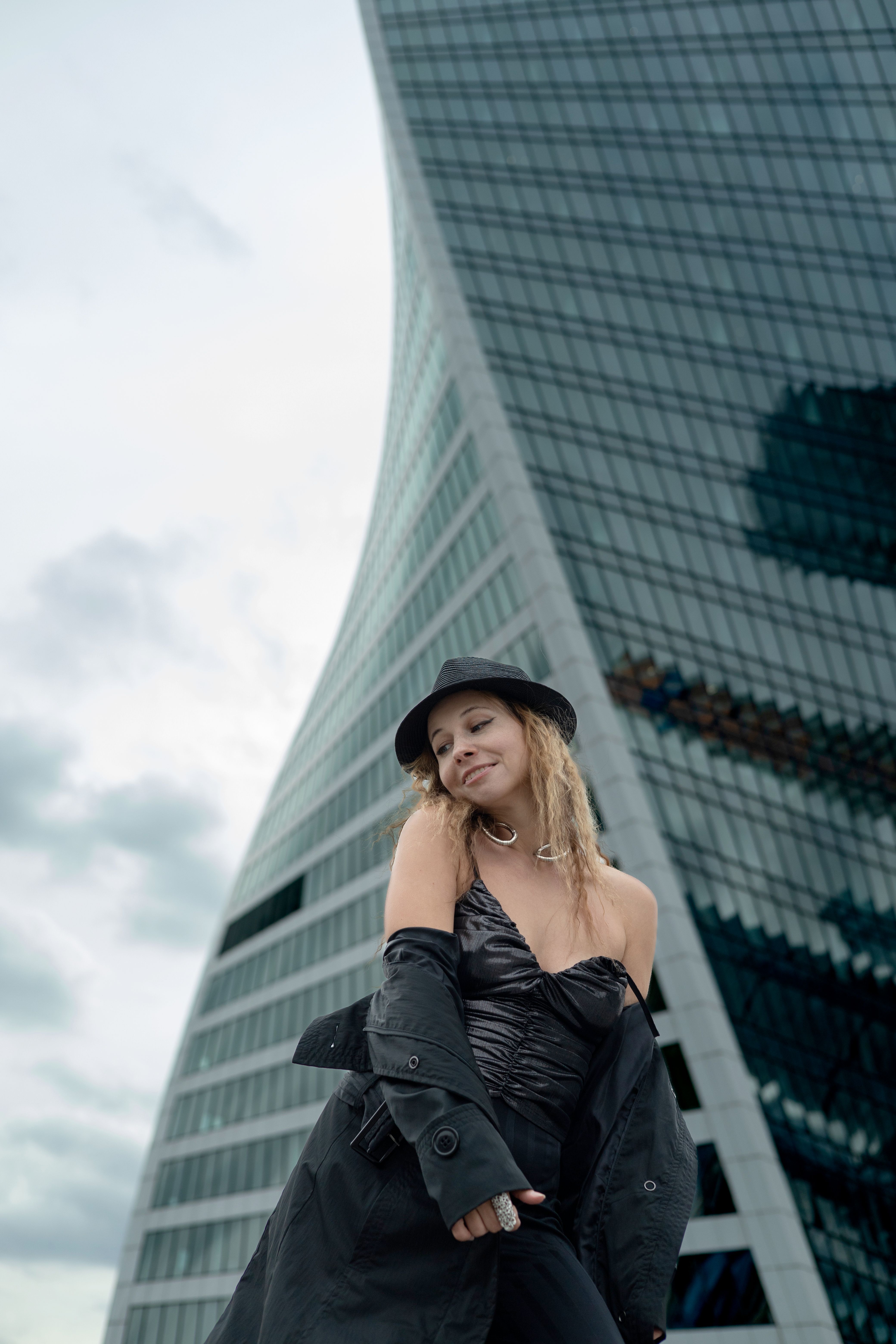 Fashionable woman in black standing in front of a modern building, representing urban style.