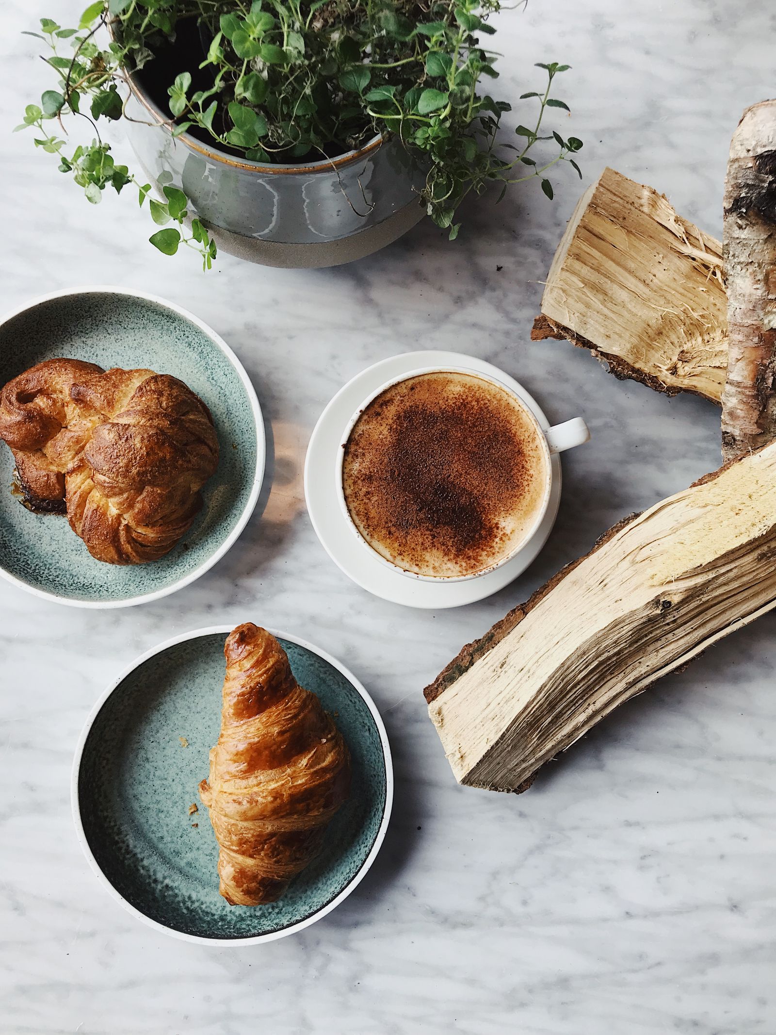 A cup of coffee beside two croissants