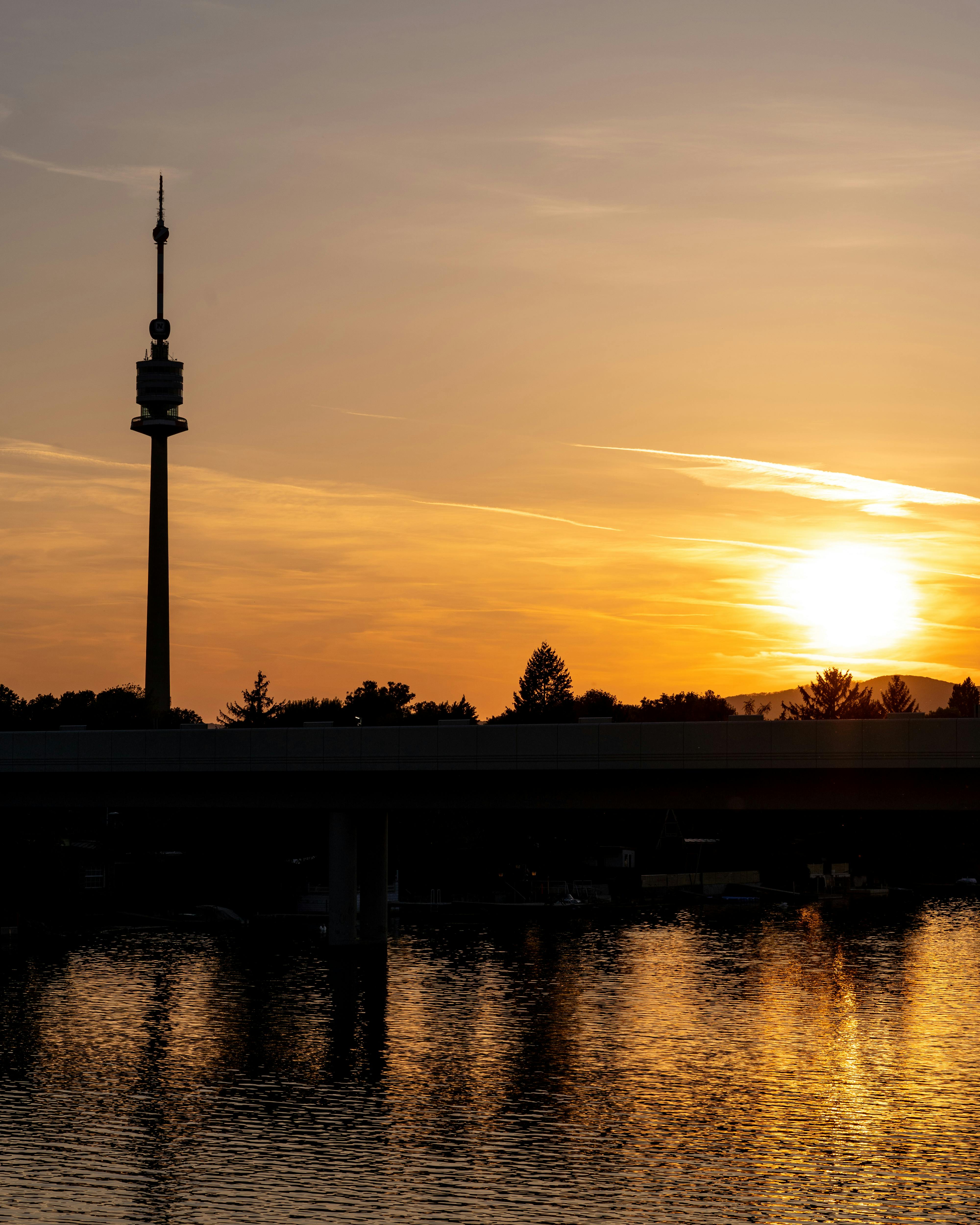 维也纳上空令人惊叹的日落，倒映着多瑙塔的轮廓在水中