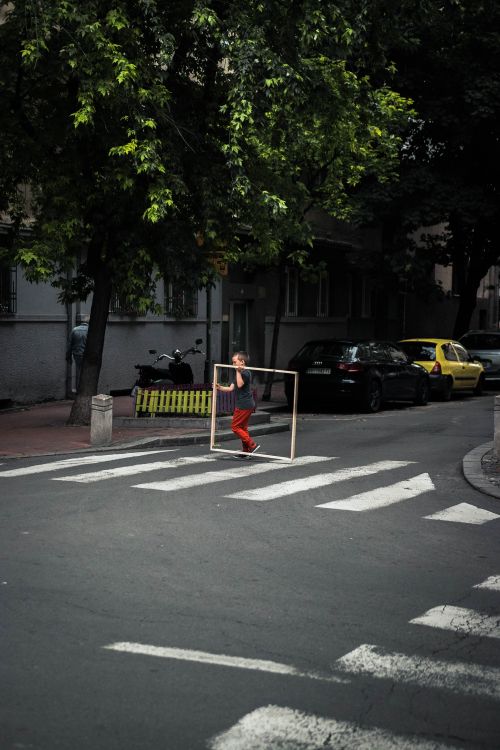 Free A child carrying a frame walks across a pedestrian crossing in an urban area. Stock Photo