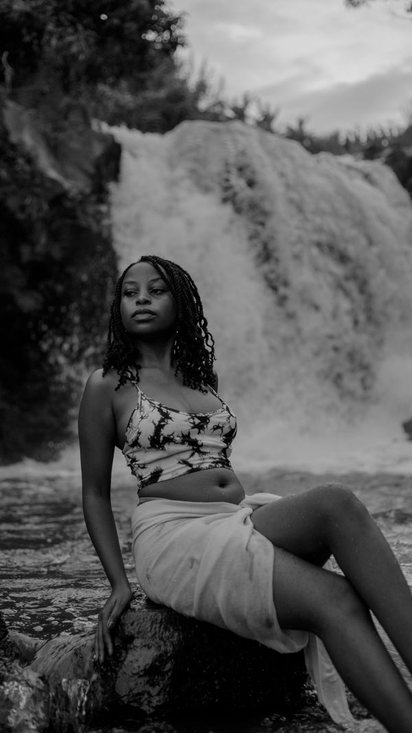 Young Woman Standing against a Splashing Waterfall · Free Stock Photo