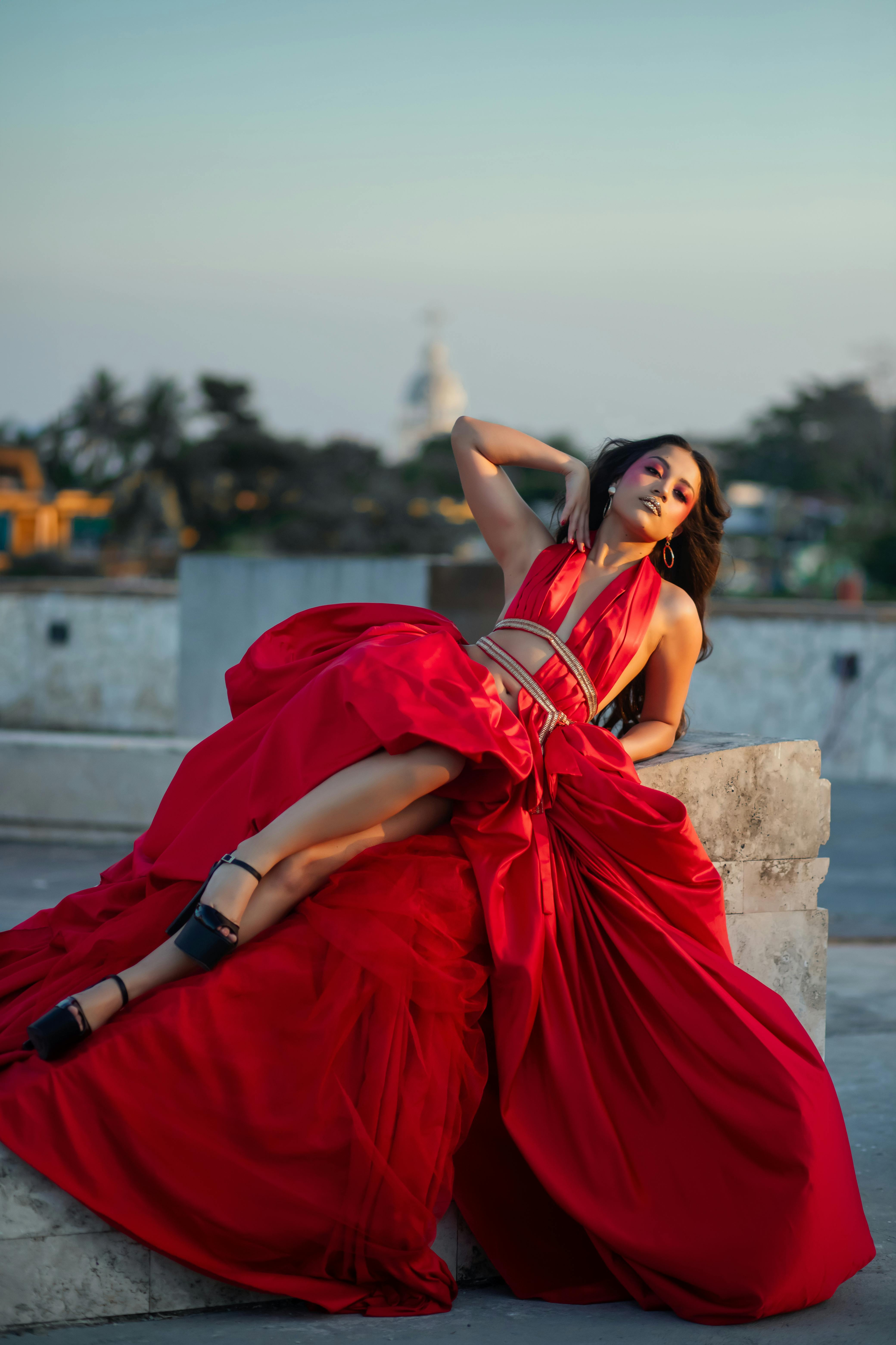 Fashion shoot of a woman in a vibrant red dress posing outdoors on a rooftop in Villahermosa, Mexico.